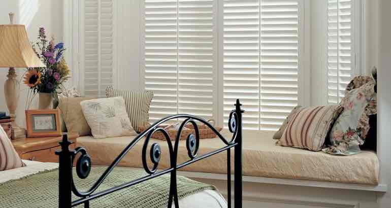 Polywood shutters in a chic bedroom bay window.